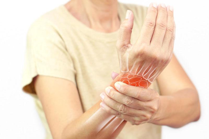Woman holding her wrist with carpal tunnel nerve pain highlighted — carpal tunnel treatment in Fort Wayne