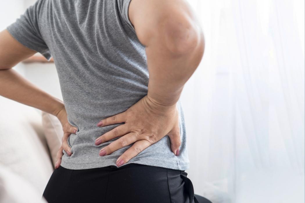Person clutching lower back from sciatic nerve pain — sciatica relief in Fort Wayne